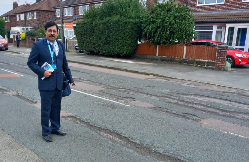 Councillor Kaushik Chakraborty standing over some potholes on Sinderland Road